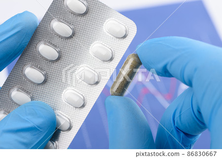 Scientist hold transparent capsule and blister pack 86830667