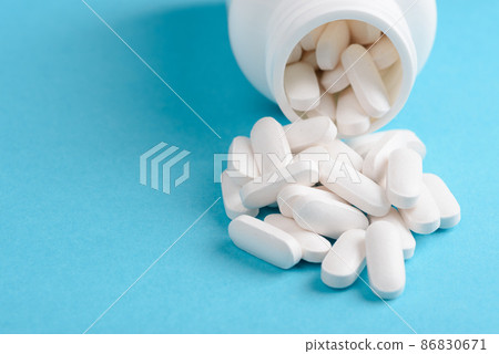 White pills with bottle on blue background with copy-space 86830671