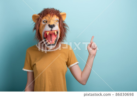 Woman in lion mask pointing with hand and index finger to the side blank space, isolated on blue 86830698