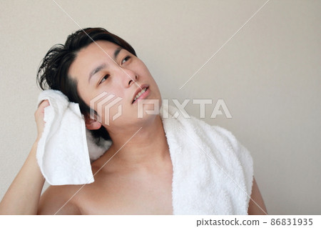 A man who dries his hair with a bath towel after taking a bath 86831935