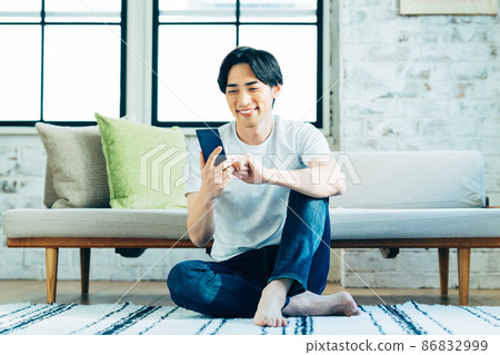 A young man looking at his smartphone in the living room A young man looking at his smartphone in the living room 86832999