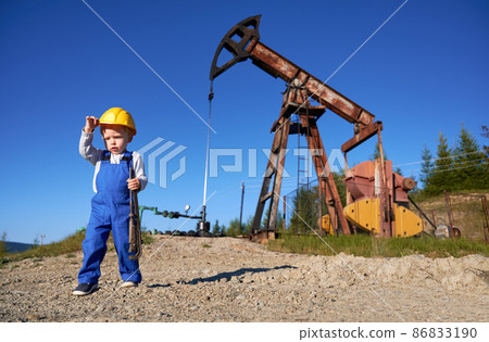 Technician blonde boy with instrument for fixing pipeline at petroleum station on background, young serviceman in professional blue coverall studying engineering occupation at oil platform Technician blonde boy with instrument for fixing pipeline at petroleum station on background, young serviceman in professional blue coverall studying engineering occupation at oil platform 86833190