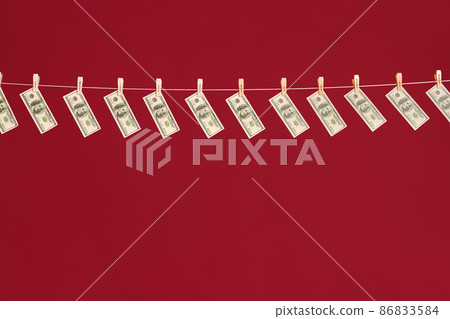 Money laundering, US dollars hanging on rope over red studio background 86833584