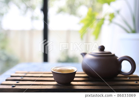 Earthenware tea cup and tea pot on wooden tray 86833869