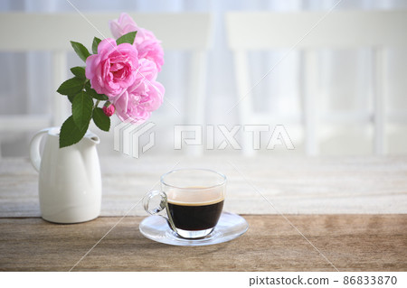 Coffee in glass cup and pink rose on wooden table indoor Coffee in glass cup and pink rose on wooden table indoor 86833870