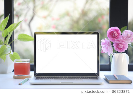 Laptop with pink rose and juice and plant on white wooden table Laptop with pink rose and juice and plant on white wooden table 86833871