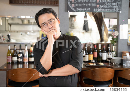 A man who runs a restaurant in a pose that is troubled with a cheek stick 86834563