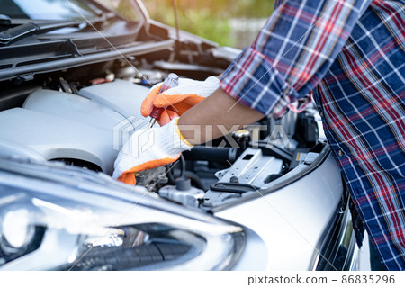 Asian auto mechanic check for repair under the hood of broken down car on the side of the road. Asian auto mechanic check for repair under the hood of broken down car on the side of the road. 86835296