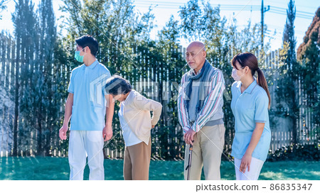 康復中心老人和護理人員在院子裡散步 86835347