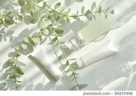 Cosmetic bottle containers packaging with green herbal leaves in shadow and light effect Cosmetic bottle containers packaging with green herbal leaves in shadow and light effect 86835996
