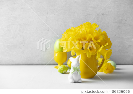 Easter eggs, bunny and Bouquet of yellow daffodils in a yellow jug on table top, Easter composition, home decor, interior, 86836066