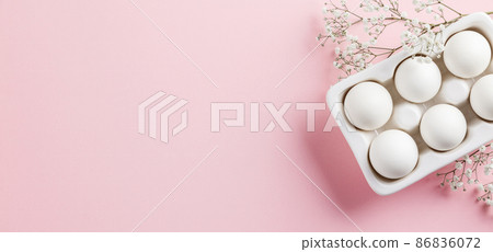 Easter concept. White eggs in ceramic holder and flowers on pink background 86836072