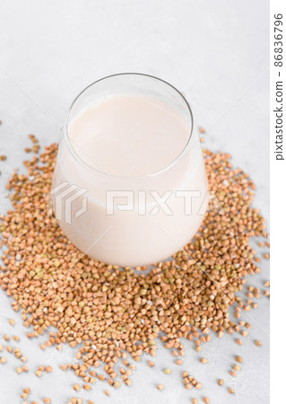 Vegan non diary buckwheat milk in glass with buckwheat groats on a white table. Veggies healthy milk product, close up 86836796