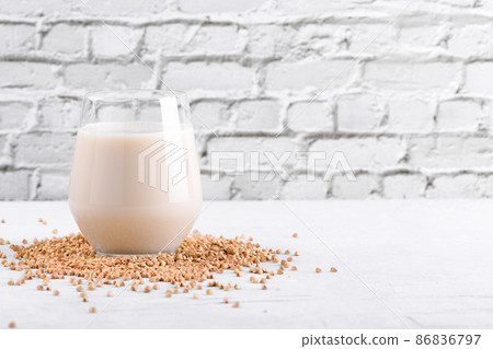 Vegan non diary buckwheat milk in glass with buckwheat groats on a white table. Veggies healthy milk product, copy space 86836797