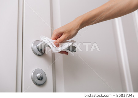 Cleaning door handles with an antiseptic wet wipe and gloves. Sanitize surfaces prevention in hospital and public spaces against corona virus. Woman hand using towel for cleaning home room door link. Cleaning door handles with an antiseptic wet wipe and gloves. Sanitize surfaces prevention in hospital and public spaces against corona virus. Woman hand using towel for cleaning home room door link. 86837342