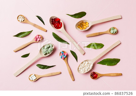 Top view Variety of vitamin and mineral pills in wooden spoon on Colored background. Top view of assorted pharmaceutical medicine pills. Dietary supplement healthcare product Top view Variety of vitamin and mineral pills in wooden spoon on Colored background. Top view of assorted pharmaceutical medicine pills. Dietary supplement healthcare product 86837526