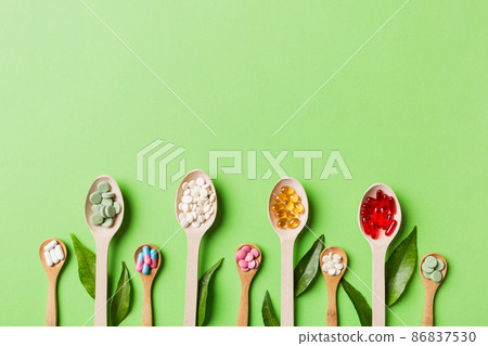 Top view Variety of vitamin and mineral pills in wooden spoon on Colored background. Top view of assorted pharmaceutical medicine pills. Dietary supplement healthcare product Top view Variety of vitamin and mineral pills in wooden spoon on Colored background. Top view of assorted pharmaceutical medicine pills. Dietary supplement healthcare product 86837530