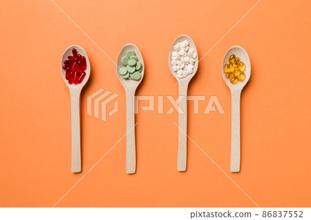 Top view Variety of vitamin and mineral pills in wooden spoon on Colored background. Top view of assorted pharmaceutical medicine pills. Dietary supplement healthcare product 86837552