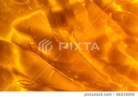 Texture of transparent yellow gel with air bubbles and waves on orange background. Concept of skin moisturizing, body care and prevention of covid19. Liquid beauty product closeup. Backdrop, flat lay Texture of transparent yellow gel with air bubbles and waves on orange background. Concept of skin moisturizing, body care and prevention of covid19. Liquid beauty product closeup. Backdrop, flat lay 86838000