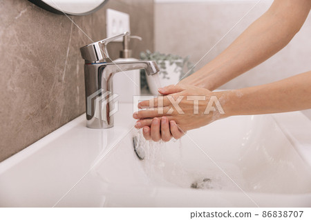 Washing hands under the flowing water tap. Washing hands rubbing with soap for corona virus prevention, hygiene to stop spreading corona virus in or public wash room. Hygiene concept hand detail. Washing hands under the flowing water tap. Washing hands rubbing with soap for corona virus prevention, hygiene to stop spreading corona virus in or public wash room. Hygiene concept hand detail. 86838707