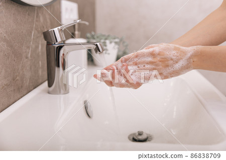 Washing hands under the flowing water tap. Washing hands rubbing with soap for corona virus prevention, hygiene to stop spreading corona virus in or public wash room. Hygiene concept hand detail. 86838709