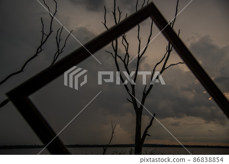 Portrait of landscape of sunset sky with dry tree looking through at empty photo frame at Bang Pra reservoir at Chonburi Province. 86838854