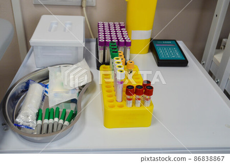 laboratory diagnostics. test tubes with multi-colored caps are in the holder. next to it is a medical vessel with needles and transfer material, tourniquets for a vein. taking venous blood laboratory diagnostics. test tubes with multi-colored caps are in the holder. next to it is a medical vessel with needles and transfer material, tourniquets for a vein. taking venous blood 86838867