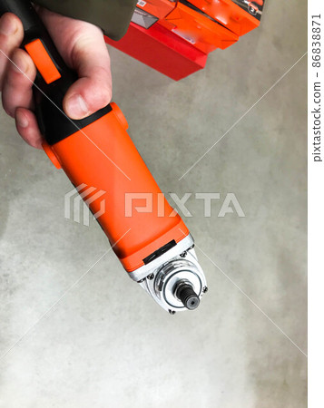 red construction tool. a man holds a tool for repair and housework with a strong hand. DIY repair. screwing into the surfac 86838871