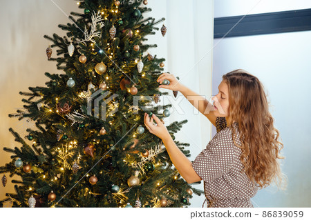 Young woman decorates the Christmas tree with toys. 86839059