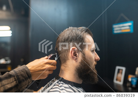 Master in barbershop makes men's haircutting with hair clipper 86839319