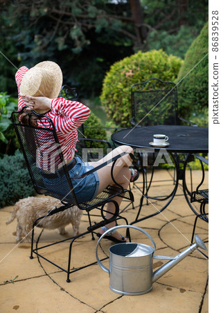 A girl is sitting and relaxing with coffee in her garden. A girl is sitting and relaxing with coffee in her garden. 86839528