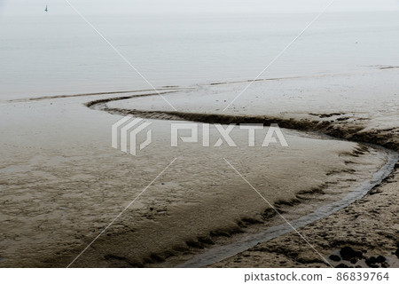 Mud grooves at the beach and shallow waters of the Atlantic Ocean in Lisbon, Portugal on a foggy day. Mud grooves at the beach and shallow waters of the Atlantic Ocean in Lisbon, Portugal on a foggy day. 86839764