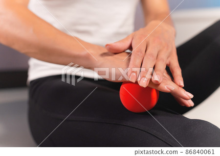 Close-up of a caucasian woman giving herself a myofascial thigh massage with a massage red ball Close-up of a caucasian woman giving herself a myofascial thigh massage with a massage red ball 86840061