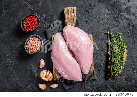 Uncooked Raw Turkey Breasts fillet steaks with herbs. Black background. Top view Uncooked Raw Turkey Breasts fillet steaks with herbs. Black background. Top view 86840073