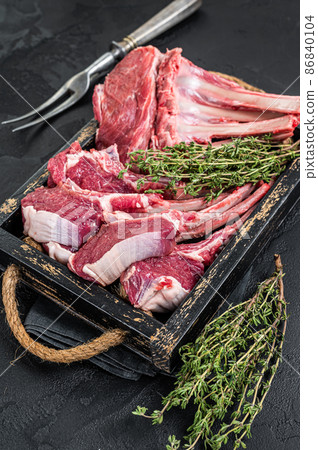 Uncooked Raw Rack and lamb, mutton rib chops in a wooden tray. Black background. Top view Uncooked Raw Rack and lamb, mutton rib chops in a wooden tray. Black background. Top view 86840104