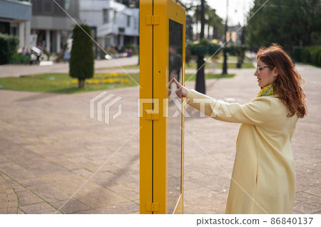 Caucasian woman using touch information board outdoors.  86840137