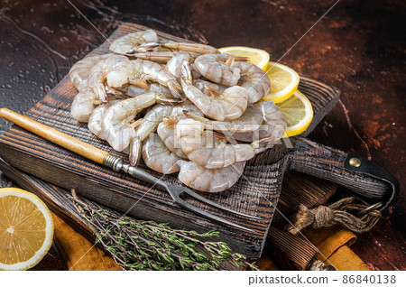 Raw tiger white shrimp prawn on board with herbs. Dark background. Top view Raw tiger white shrimp prawn on board with herbs. Dark background. Top view 86840138