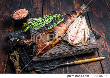 Cut Hot smoked fish on a wooden board with rosemary. Dark wooden background. Top view 86840283