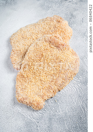 Raw chicken schnitzel Escalope in breadcrumbs. White background. Top view Raw chicken schnitzel Escalope in breadcrumbs. White background. Top view 86840422