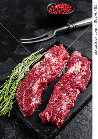 Raw Machete steak or hanging tender cut with herbs. Black background. Top view Raw Machete steak or hanging tender cut with herbs. Black background. Top view 86840483