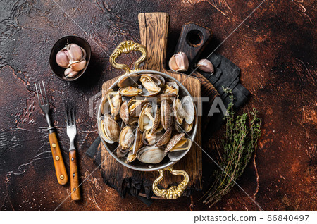 Garlic white wine shells Clams, vongole in a skillet with herbs. Dark background. Top view Garlic white wine shells Clams, vongole in a skillet with herbs. Dark background. Top view 86840497