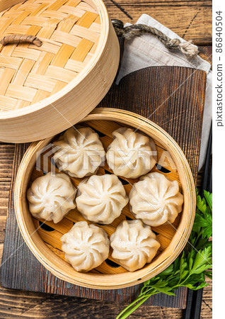 Momo dumplings in a bamboo steamer. Wooden background. Top view 86840504