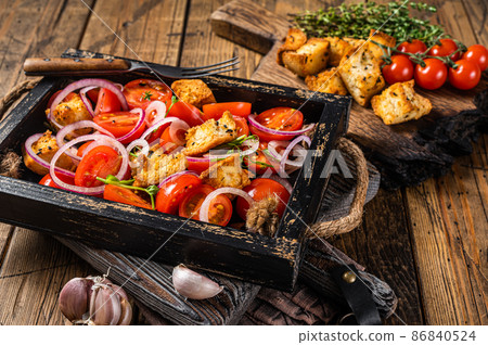Traditional Italian Panzanella salad with tomatoes, onion and bread Croutons in wooden tray. Wooden background. Top view Traditional Italian Panzanella salad with tomatoes, onion and bread Croutons in wooden tray. Wooden background. Top view 86840524
