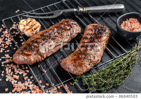 BBQ grilled Lamb tenderloin fillet meat on grill, mutton loin steak. Black background. Top view BBQ grilled Lamb tenderloin fillet meat on grill, mutton loin steak. Black background. Top view 86840583