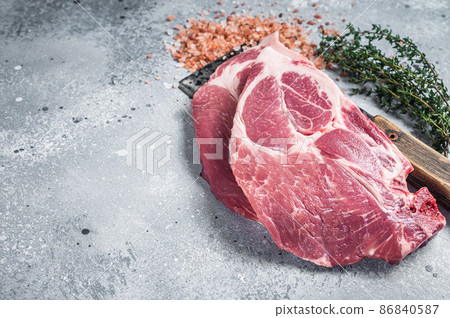 Fresh pork tender steaks from raw neck meat on butcher meat cleaver with salt and thyme. Gray background. Top view. Copy space Fresh pork tender steaks from raw neck meat on butcher meat cleaver with salt and thyme. Gray background. Top view. Copy space 86840587