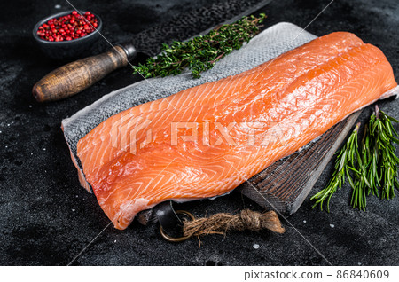Fresh raw salmon fillet fish on cutting board with knife. Black background. Top view Fresh raw salmon fillet fish on cutting board with knife. Black background. Top view 86840609