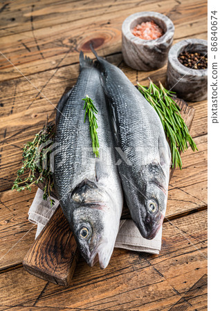 Seabass fresh raw fish on a wooden cutting board with rosemary. wooden background. Top view Seabass fresh raw fish on a wooden cutting board with rosemary. wooden background. Top view 86840674