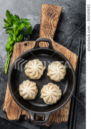 Dim sum stuffed meat dumplings in a pan with herbs. Black background. Top view Dim sum stuffed meat dumplings in a pan with herbs. Black background. Top view 86840683
