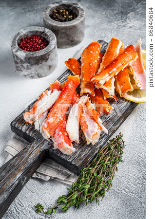 Cooked King Crab legs meat on a wooden board with herbs. White background. Top view Cooked King Crab legs meat on a wooden board with herbs. White background. Top view 86840684