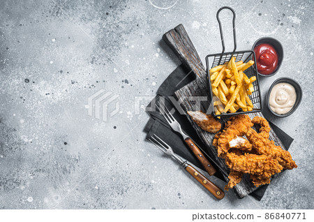 Breaded chicken strips with french fries and ketchup. Gray backgrund. Top view. Copy space 86840771